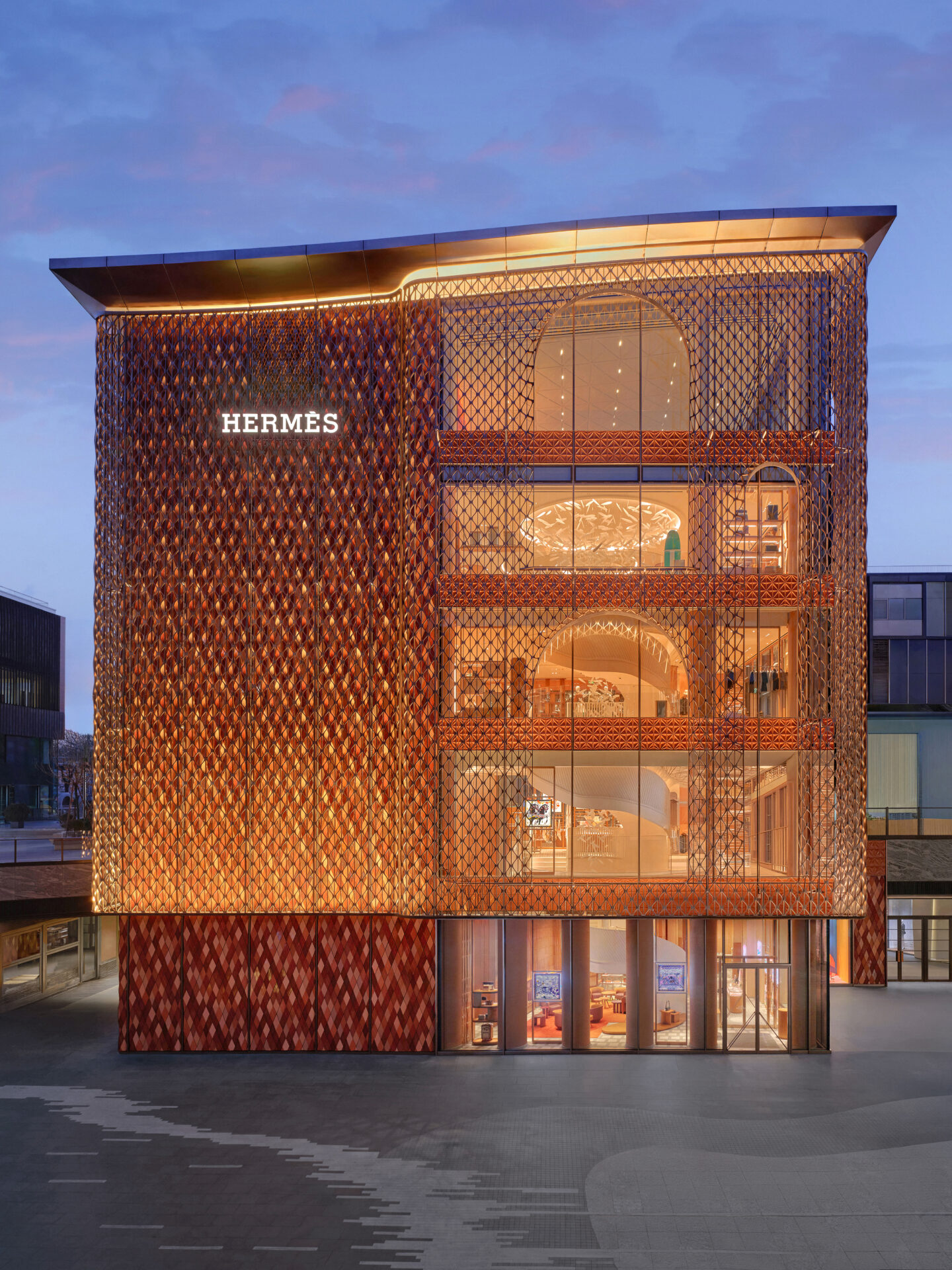 Completed Hermès Sanlitun flagship façade in Beijing, illuminated at dusk.